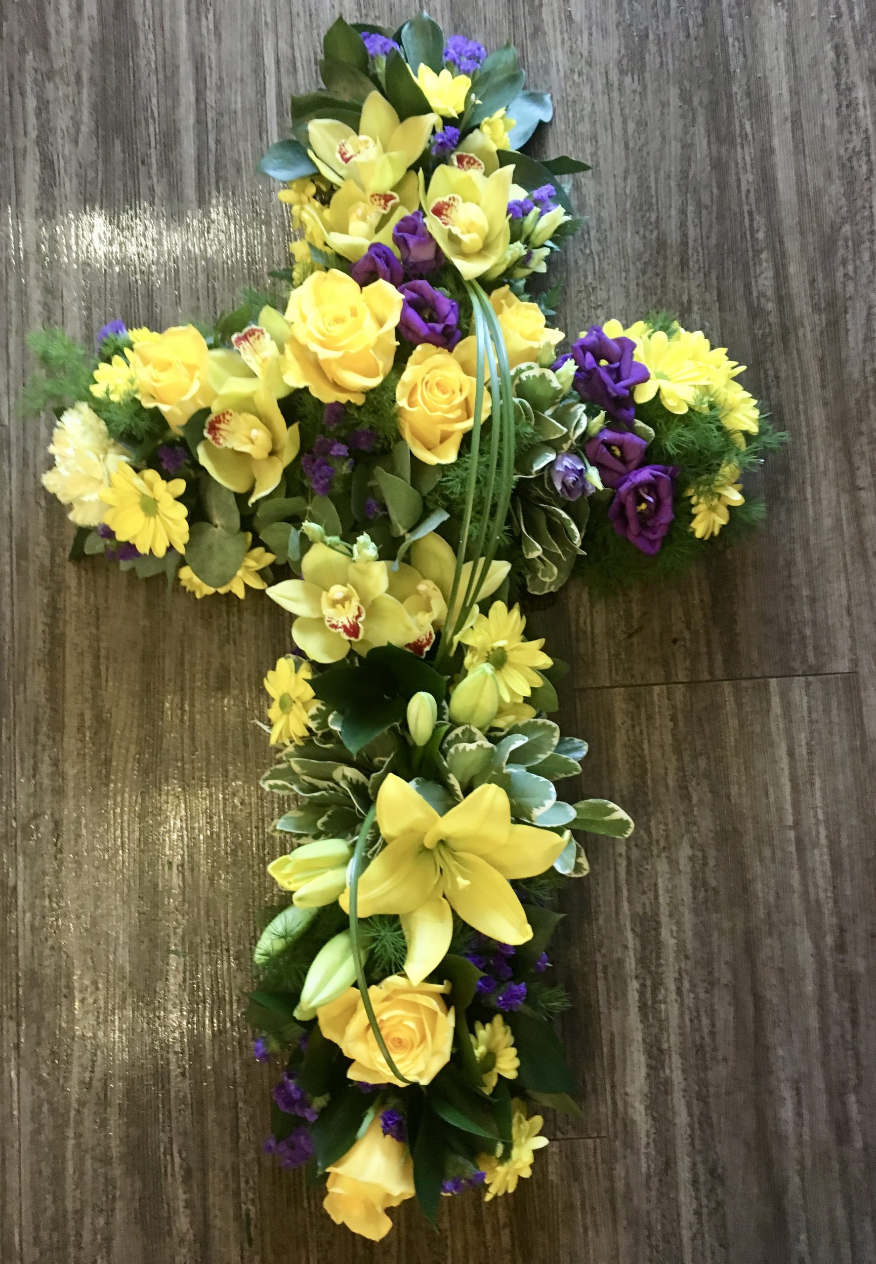 A traditional massed cross with a spray in the centre. this item can be ribbon or foliage edged with colours of your choice. 24 hours notice required.
