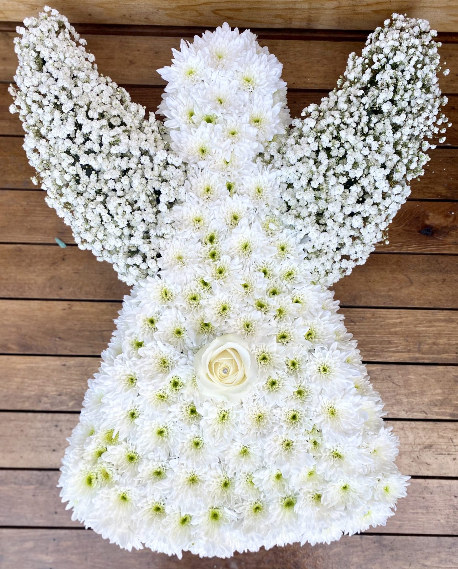A lovely massed angel in white with touches of feathers and glitter on the flowers Colour of you choice 24hrs notice required Due to seasonal variations some items may be substituted to produce a display of equal quality and value. Professionally arranged by our expert florists with care. Delivered by hand by our own driver. Click & collect is also available