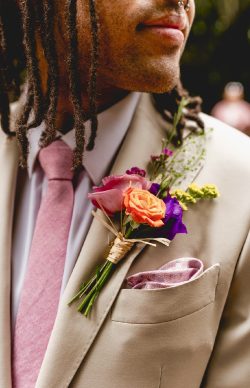 Vibrant flower buttonhole tied with raffia